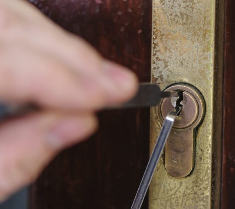 A man uses lockpicking tools to pick the lock of a house.