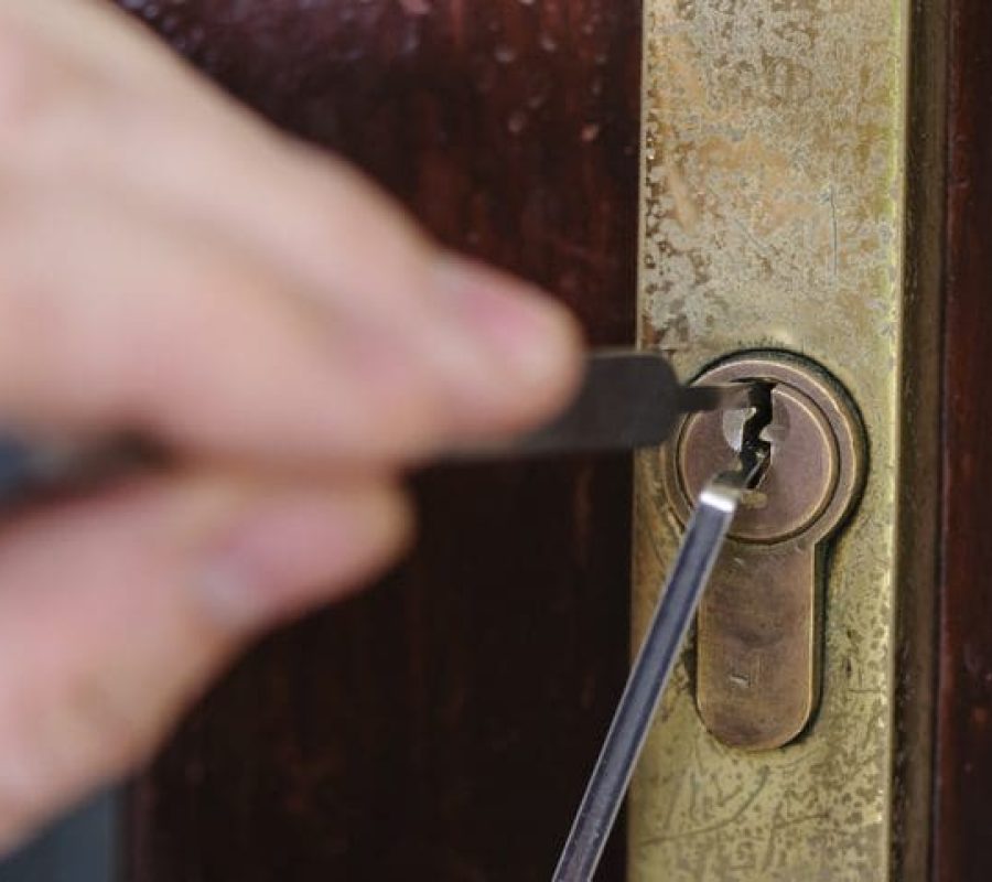 A man uses lockpicking tools to pick the lock of a house.